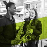 Two young people playing saxophones in a music shop