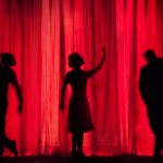 3 performers silhouetted behind a red curtain on stage